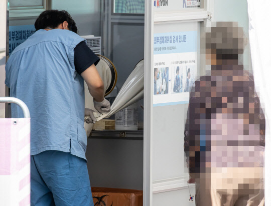 27일 서울 국립중앙의료원 선별진료소에서 신종 코로나바이러스 감염증(코로나19) 검체 검사를 마친 의료진이 방역 작업을 하고 있다.  연합뉴스